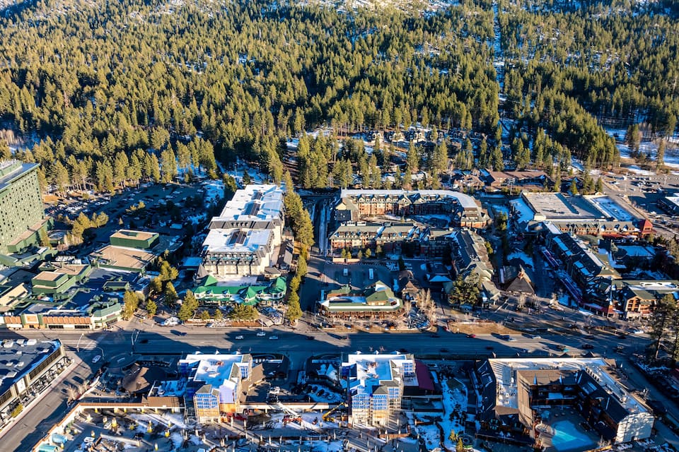 Oversigtsbillede af en by med tæt skov i baggrunden, en blanding af erhvervs- og boligbygninger, samt en hovedvej der løber gennem midten.