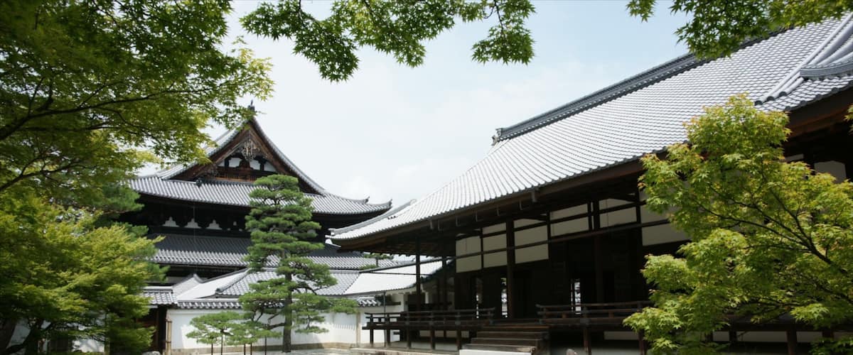 A traditional Japanese temple with a tiled roof, surrounded by trees and rocks.
