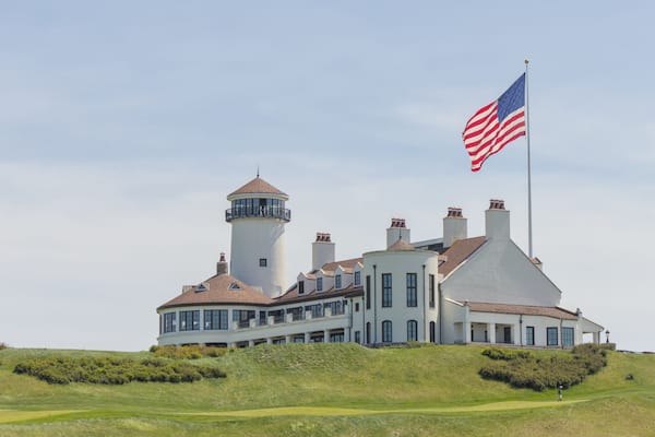 white building on green meadow grass hill next to american flag of the united states of america usa golf course next to hudson river bayonne new jersey