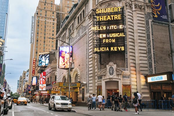 A busy urban street with prominent buildings, including a theater and a restaurant.