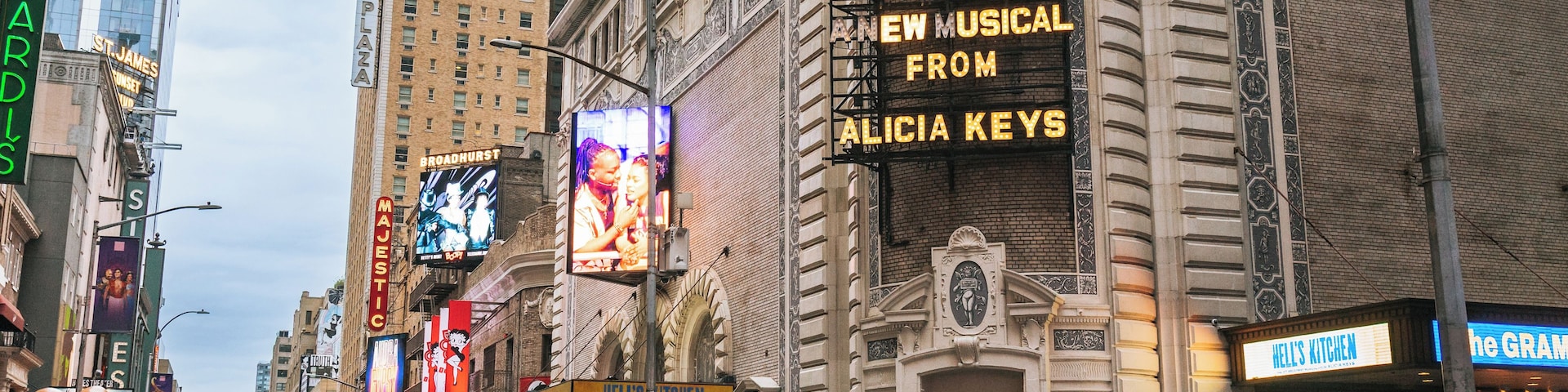 Uma rua urbana movimentada com edifícios imponentes, incluindo um teatro e um restaurante.