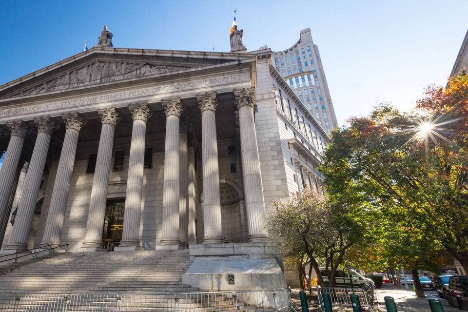 A neoclassical building with large columns and a statue on top.