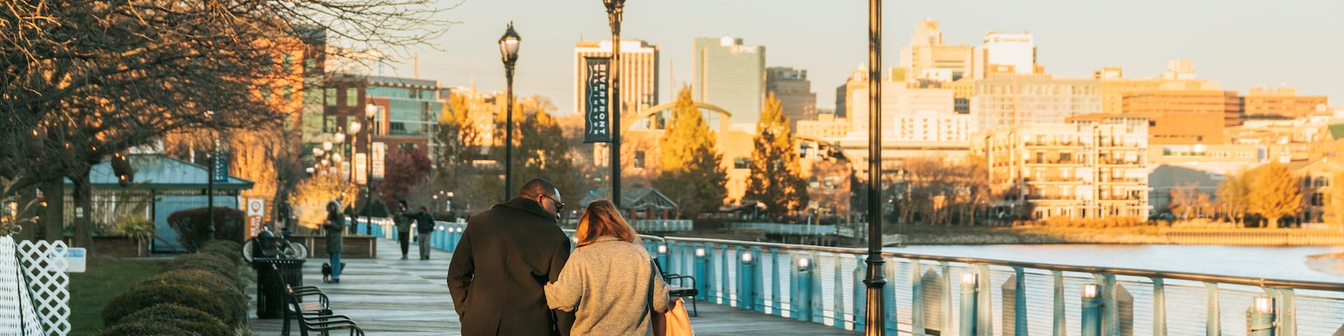 Wilmington Riverwalk featuring a sunset as well as a couple