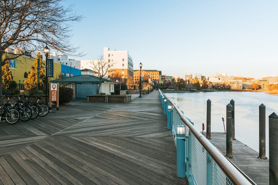 A wooden boardwalk by a river with bike rentals and a covered seating area.