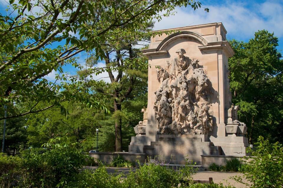 A large stone monument with intricate carvings, surrounded by lush greenery and trees.
