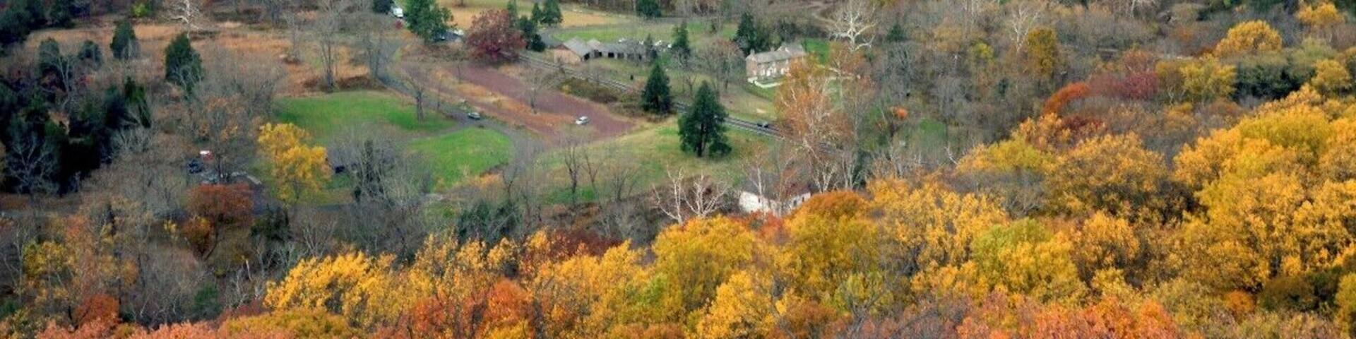 A valley with a river, autumn-colored trees, and scattered buildings.