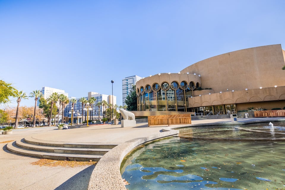 A modern building with circular windows and a fountain in front.