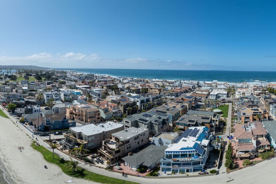 Uma vila costeira com praia, marina e edifícios residenciais.