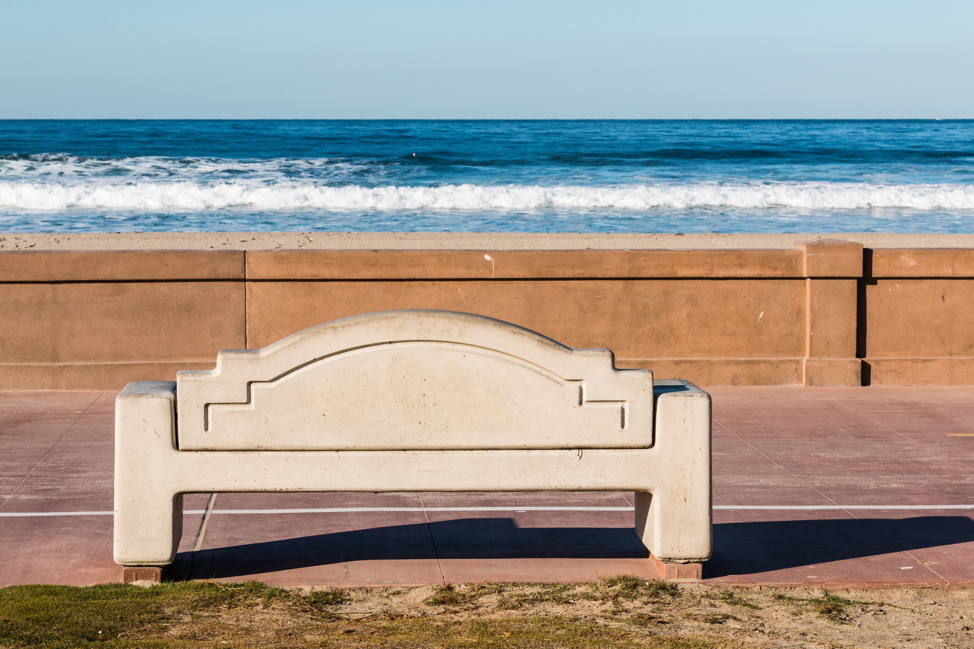 Bench on the Mission Beach boardwalk in San Diego, California with ocean waves in the background.