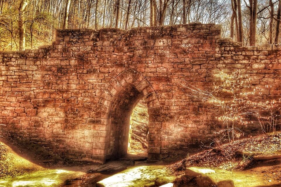 An old stone bridge in a forested area.