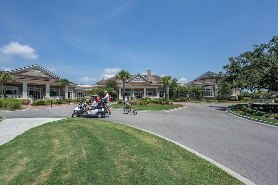 Zona residencial con dos casas grandes, un carrito de golf y un ciclista.