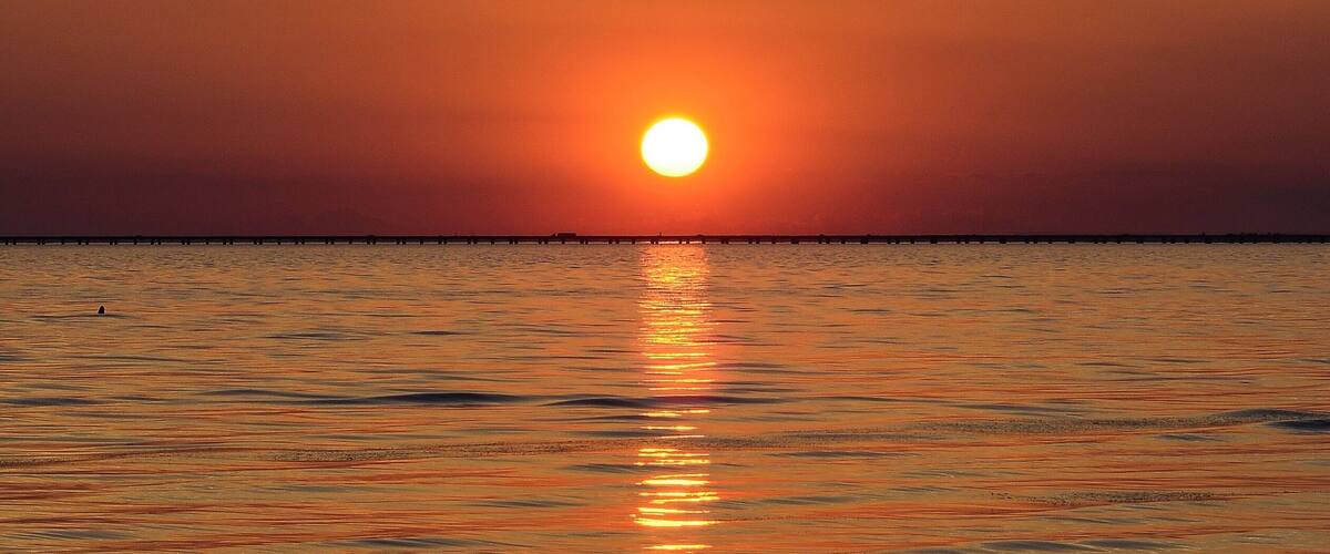 A sunset over a calm sea with a visible horizon line.