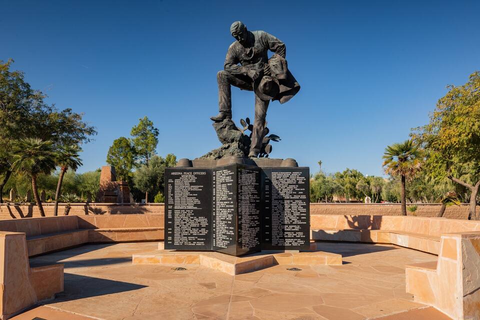 A bronze statue of a man in a suit, with a list of names on the base.