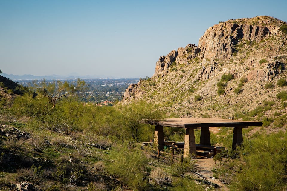 A wooden structure on a hillside overlooking a cityscape.