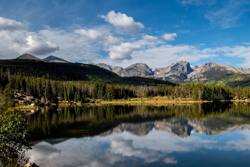 A mountain range, a calm lake, and dense forest.