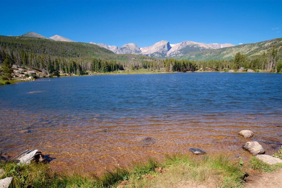 Un lago de montaña cristalino rodeado de colinas boscosas.