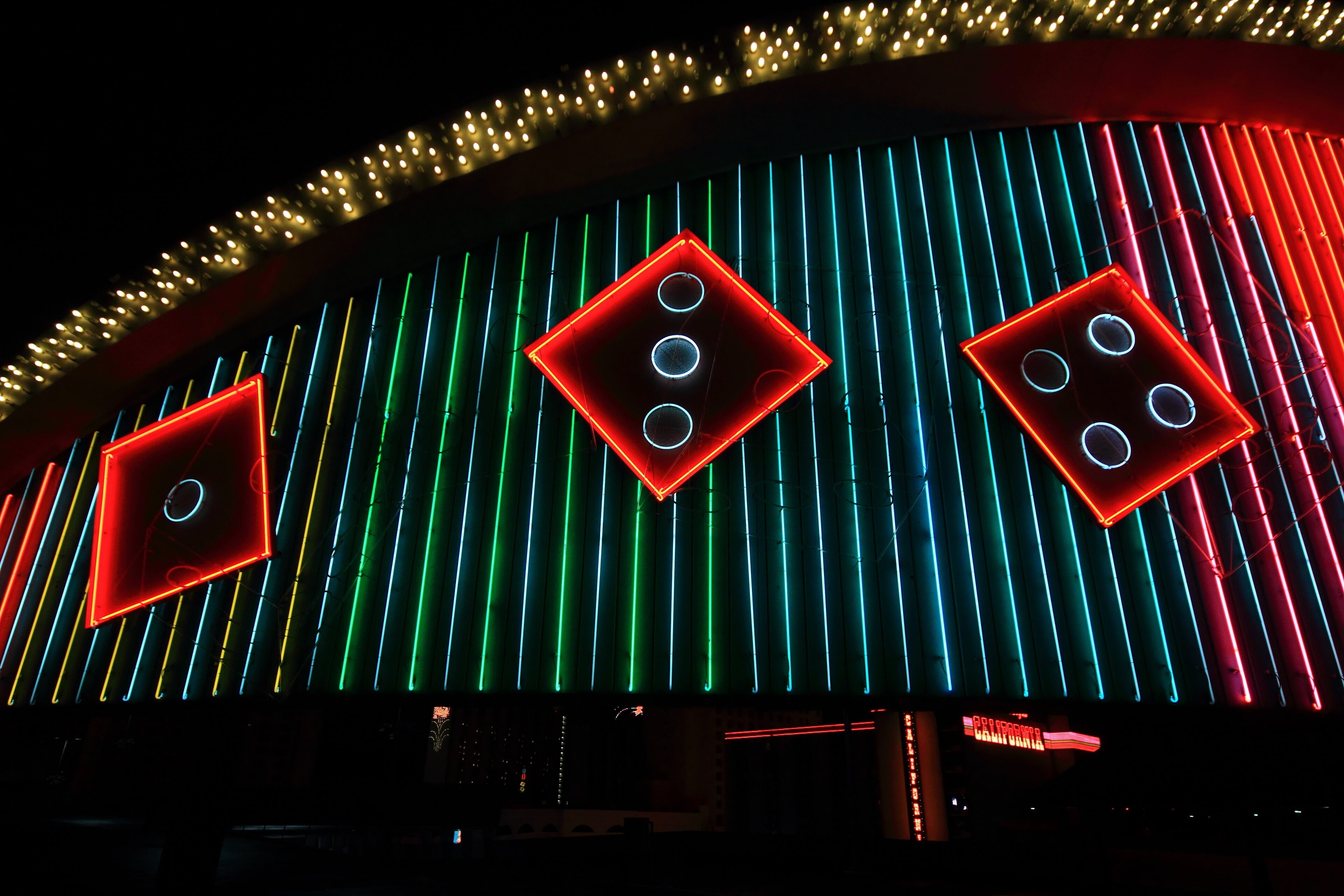 Colorful neon advertises gambling opportunities in Las Vegas with dice rolling across a sign.