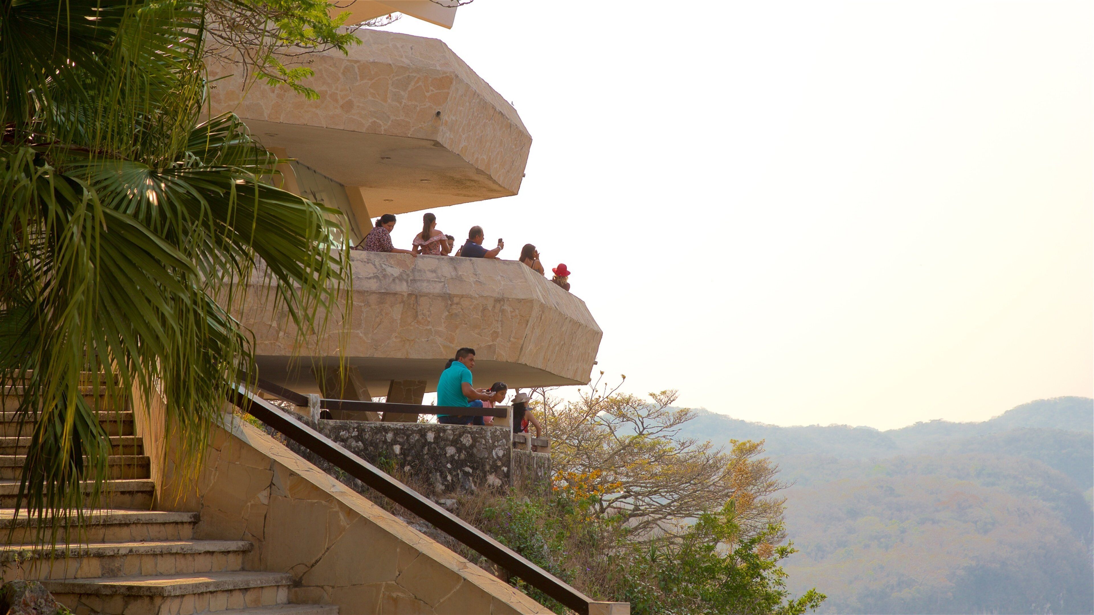A stone staircase leading up to a viewing platform with people sitting and taking photos.