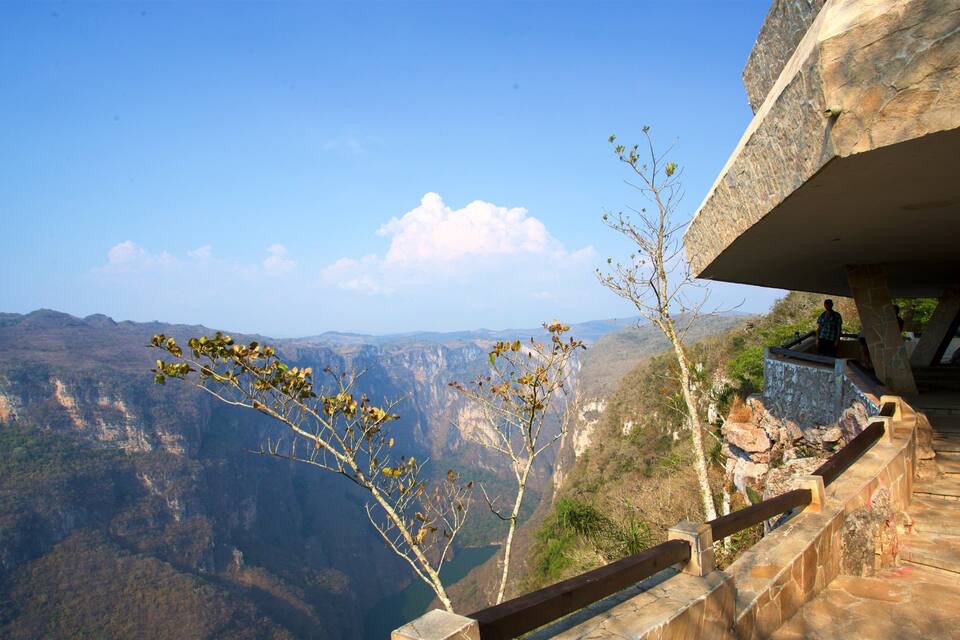 A scenic overlook with a view of a canyon, a stone staircase, and a wooden railing.