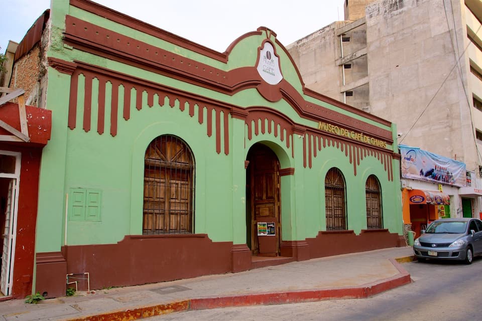 Un bâtiment aux couleurs vert et marron, doté de fenêtres en arc de cercle et d’une enseigne sur laquelle on peut lire « Museo del Café de Chiapas ».