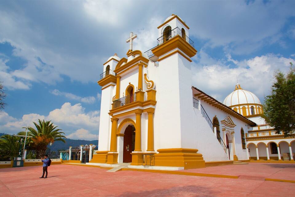 Uma igreja branca com detalhes amarelos e uma torre de sino.