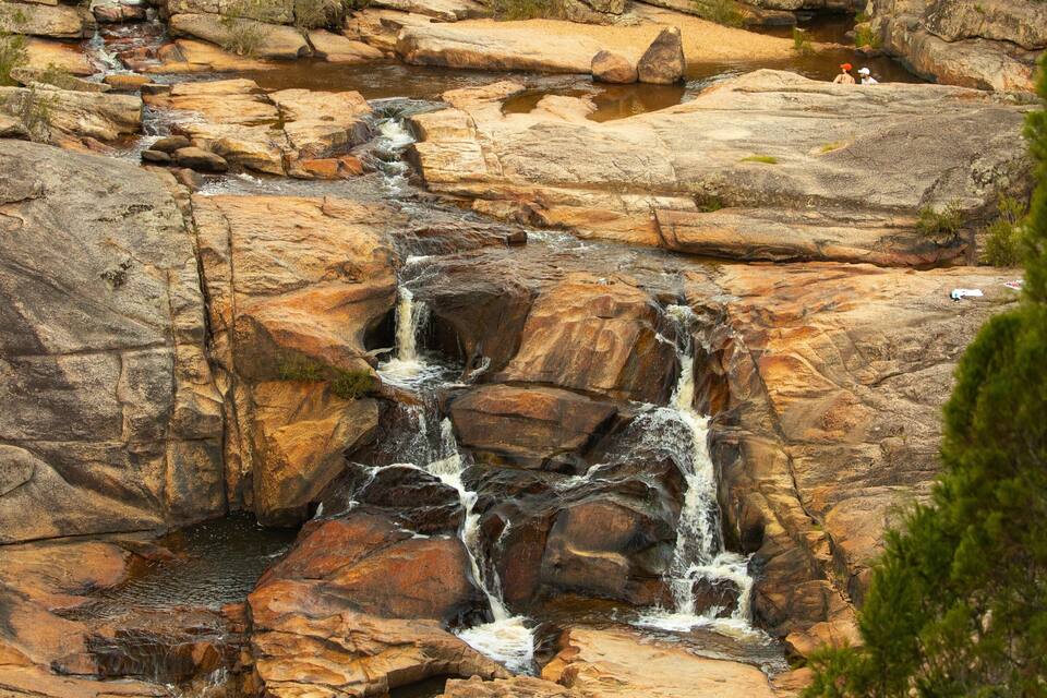 A waterfall cascading over large rocks in a natural setting.