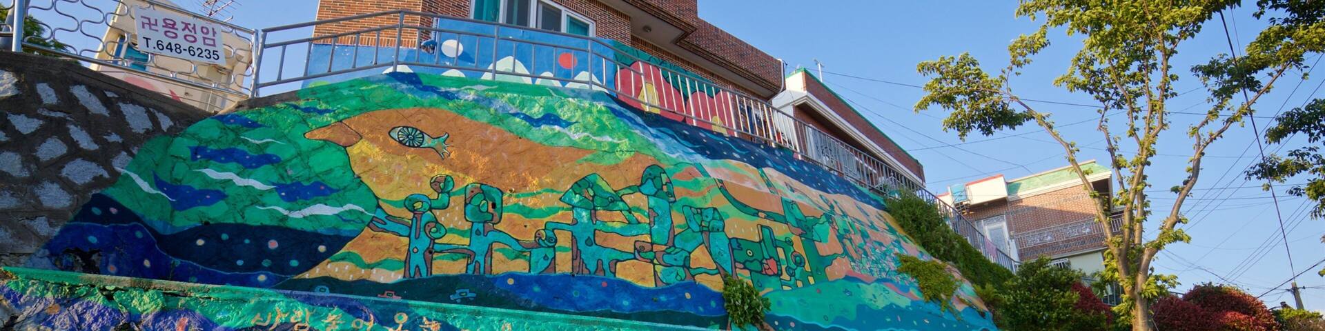 Un mural colorido en una pared de piedra con un edificio al fondo.