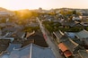 sunset drapes over Jeonju Hanok Village, silhouetting traditional houses against a twilight sky, as a bustling street comes alive under the warm, atmospheric light.