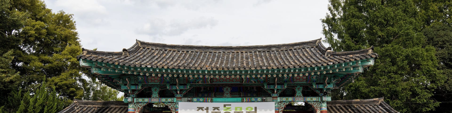 Puerta tradicional coreana en la entrada del zoológico de Jeonju, con visitantes.