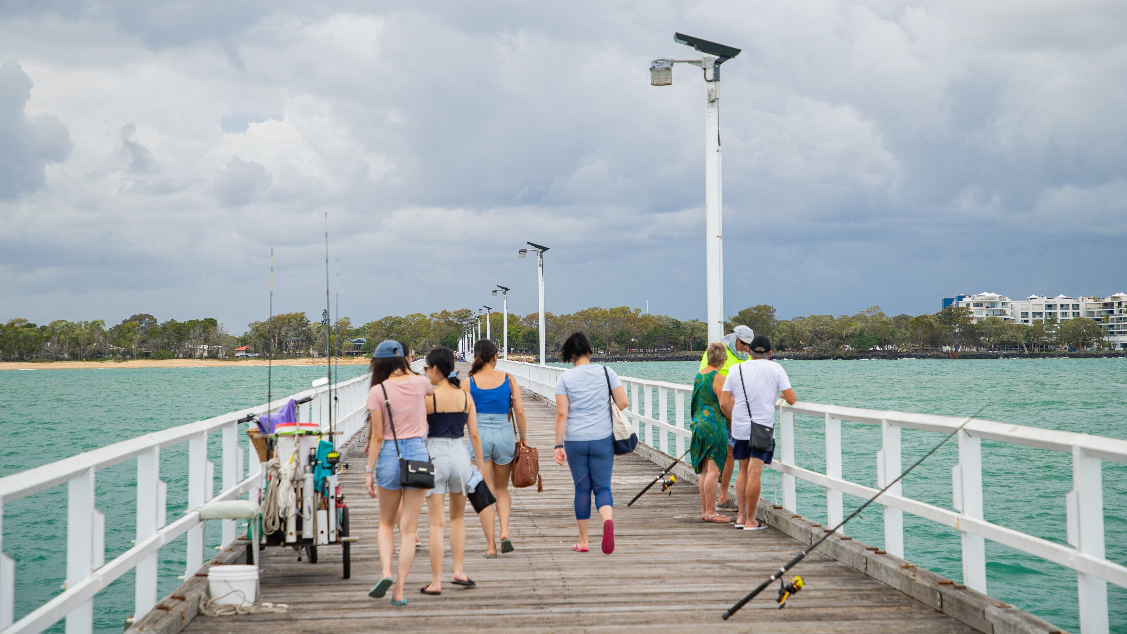 Urangan Pier which includes fishing and general coastal views as well as a small group of people