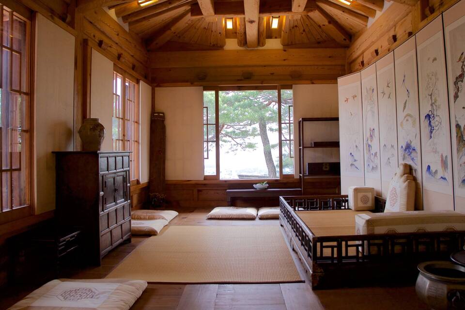 Um quarto japonês tradicional com esteiras de tatame, mobiliário de madeira e arte em caligrafia.