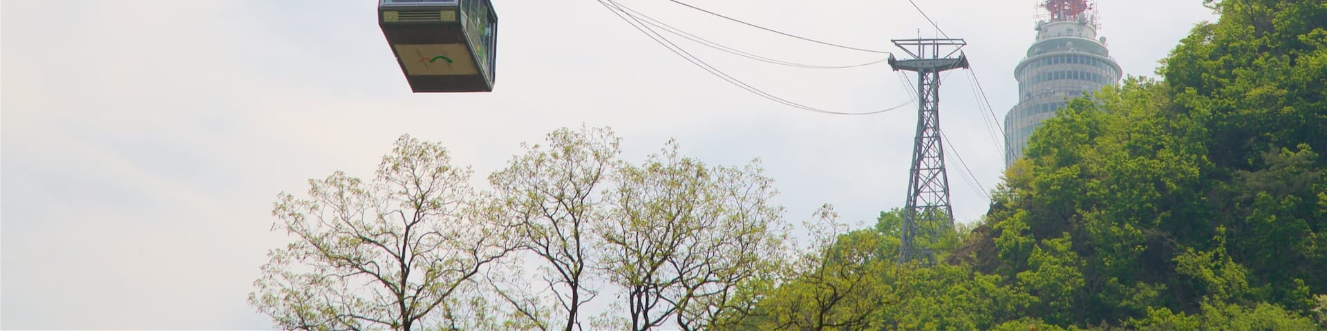 A cable car moving through the air with a tall tower in the background.