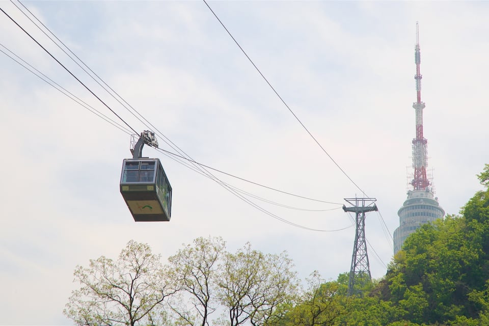 A cable car moving through the air with a tall tower in the background.