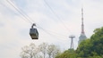 A cable car moving through the air with a tall tower in the background.