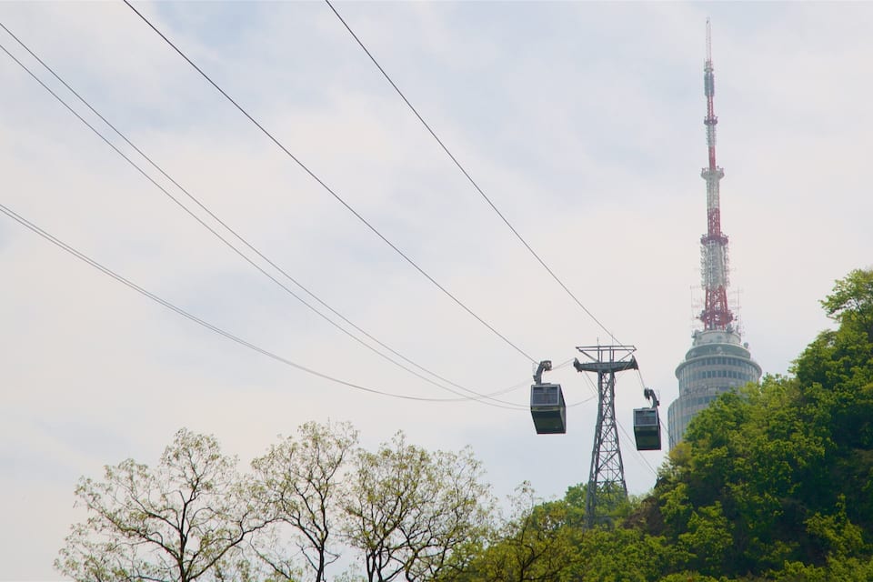 A tower with a red spire, surrounded by trees and power lines.