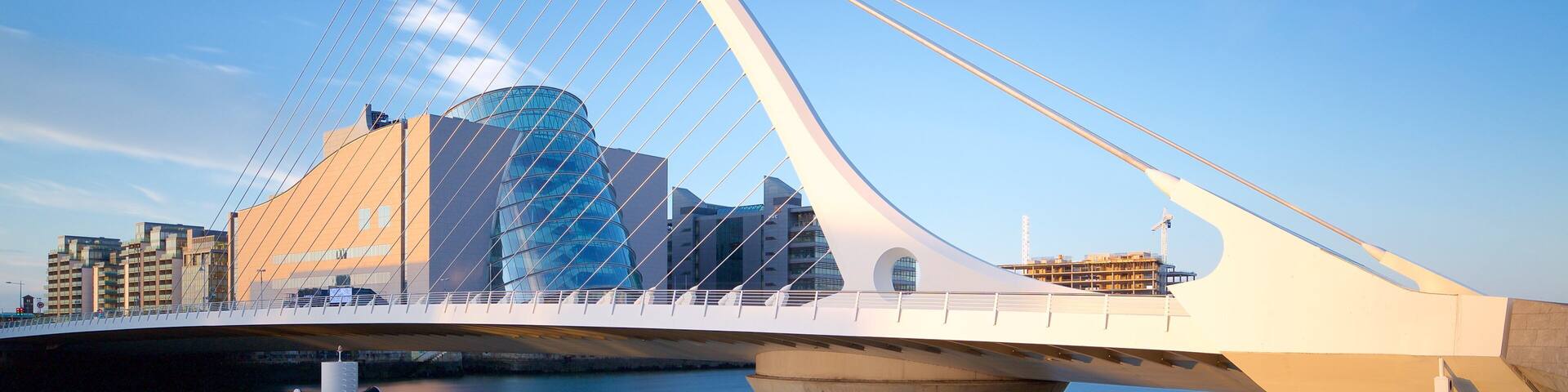 A modern bridge with a unique cable design, a glass building, and a construction crane in the background.