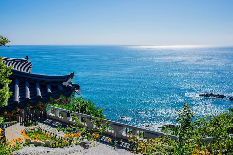 A traditional building with a tiled roof overlooking a clear blue sea.