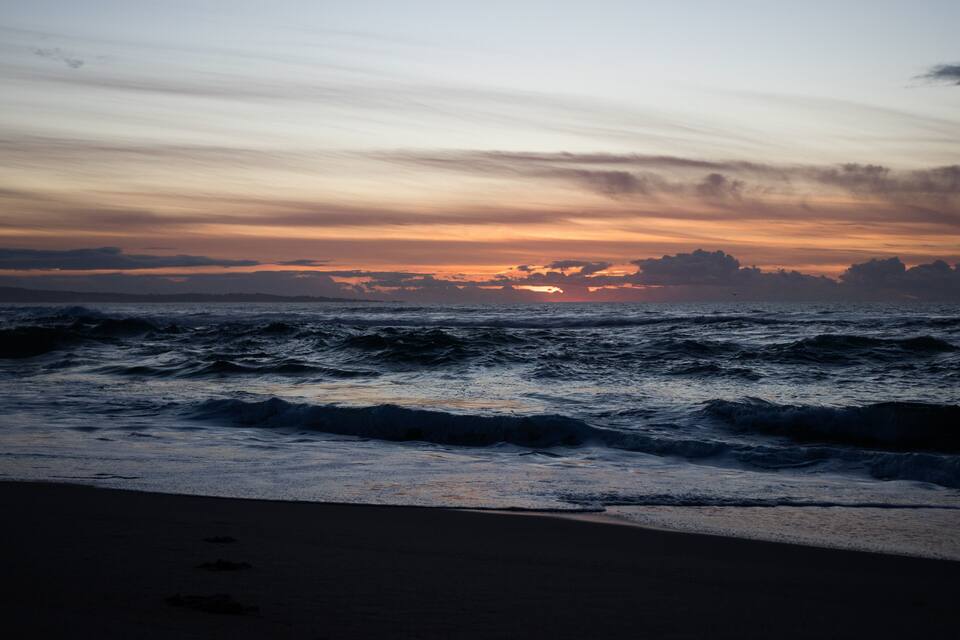 A beach with waves at sunset.