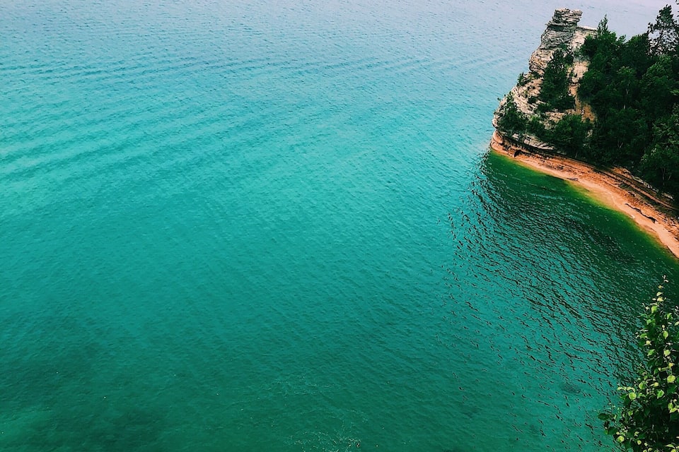 Un paisaje costero con aguas turquesas cristalinas, una playa arenosa y vegetación circundante.