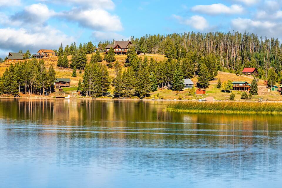 A lakeside village with houses on a hillside, surrounded by dense forest.