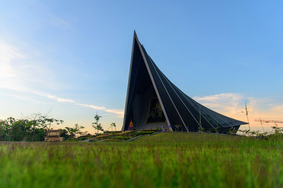 Una estructura arquitectònica moderna amb disseny triangular, envoltada d'una zona verda i arbres.