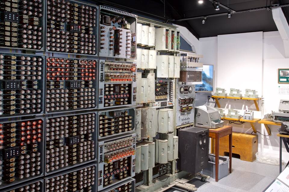 A large display of vintage electronic equipment, including rows of old radios and other devices, in a museum or exhibition setting.