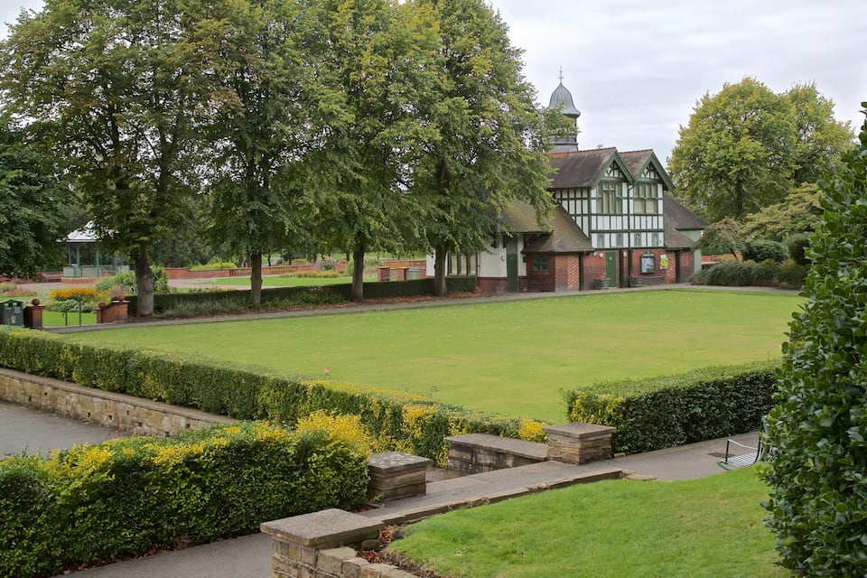 Um gramado bem cuidado com um edifício de estilo Tudor tradicional ao fundo.