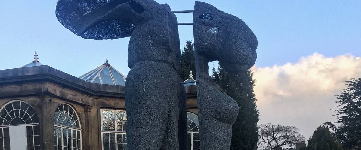 A sculpture of two figures in a garden.
