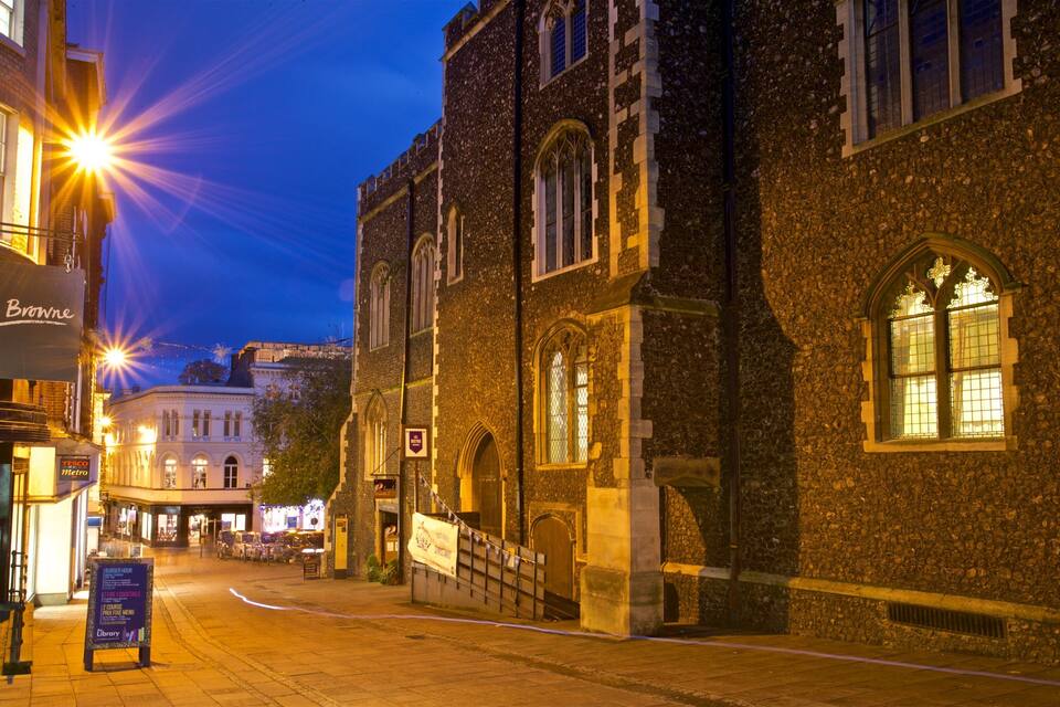 A historic street at dusk with illuminated buildings and a sign for 'Philip Browne'.
