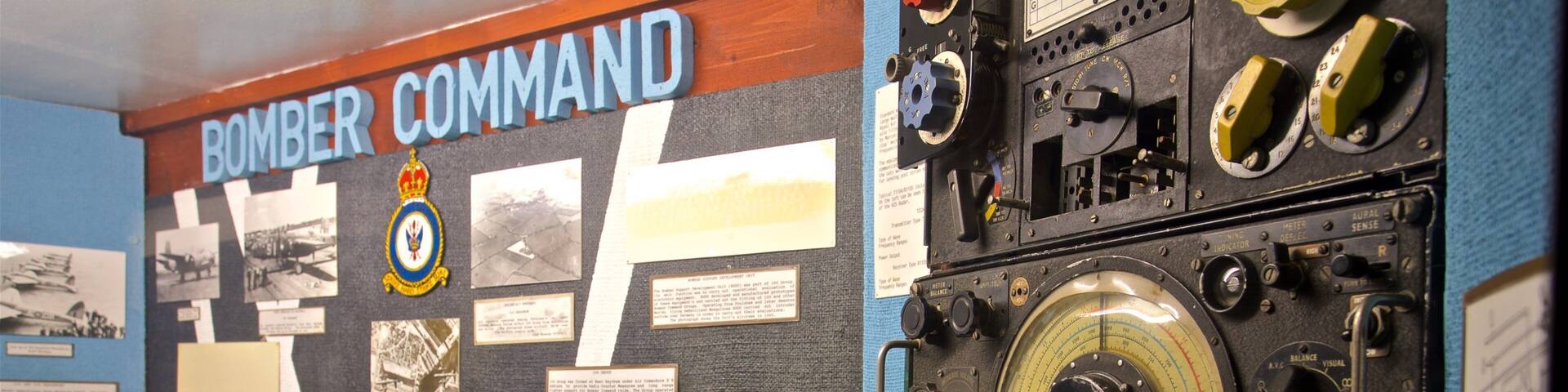 Pantalla de comando de bombarderos con fotografías históricas, mapas e instrumentos mecánicos.