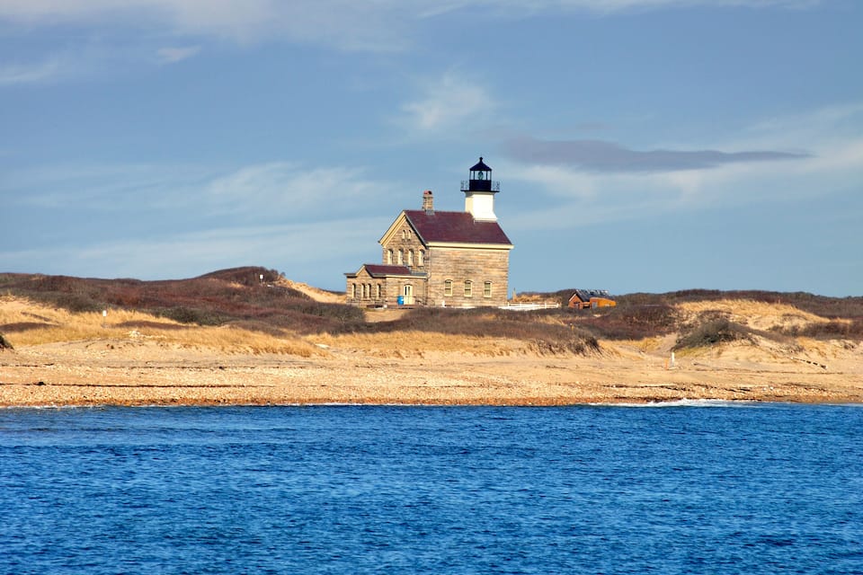 A lighthouse on a sandy beach with a clear blue sky.