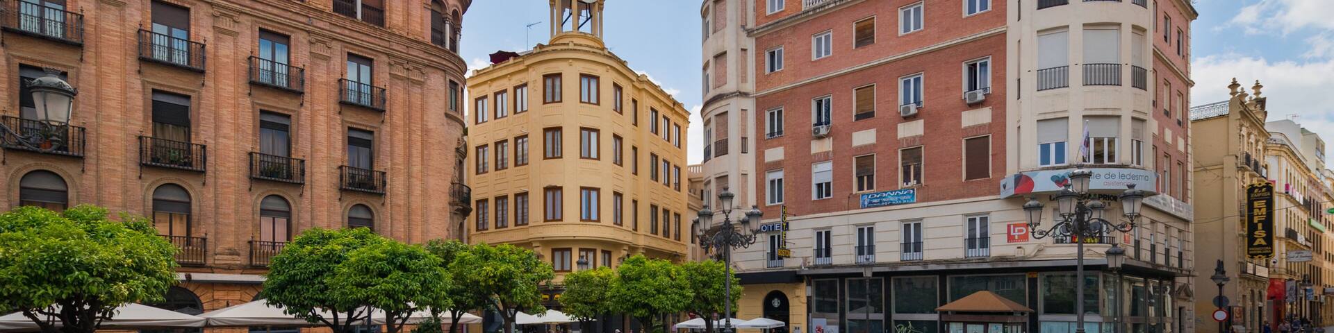 A bustling square with historic buildings, including a clock tower and a café.