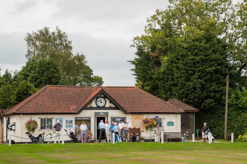 A building with a clock, a sign reading "Video Lessons," and a golf club sign.