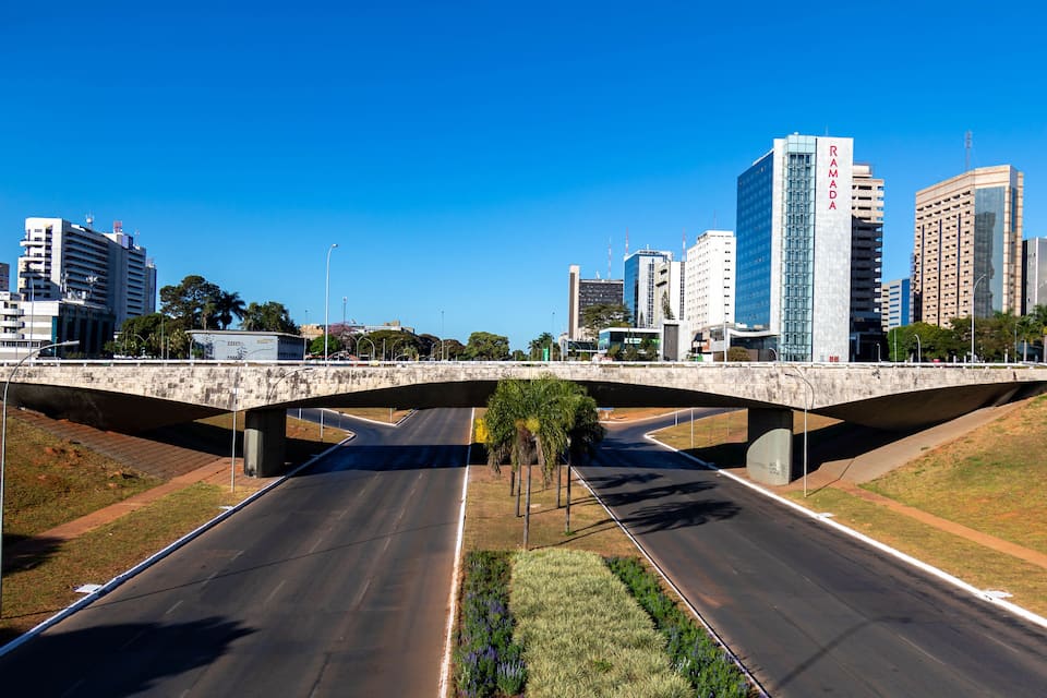 A bridge over a highway with modern buildings in the background.